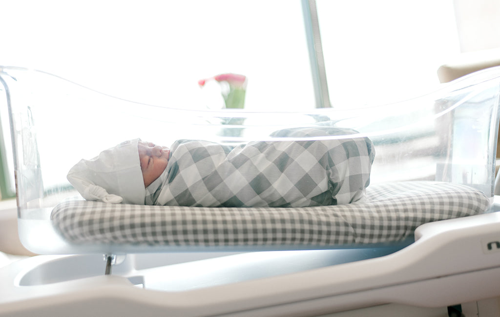 Newborn baby sleeping in their nest wrapped with a baby swaddle blanket